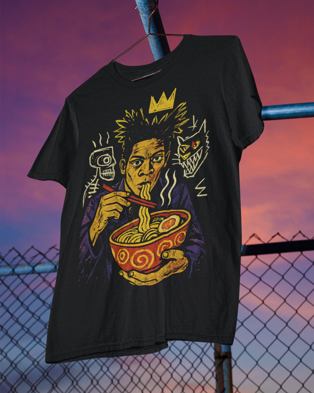 Black t-shirt with a graphic design of a person eating ramen noodles against a sunset sky.