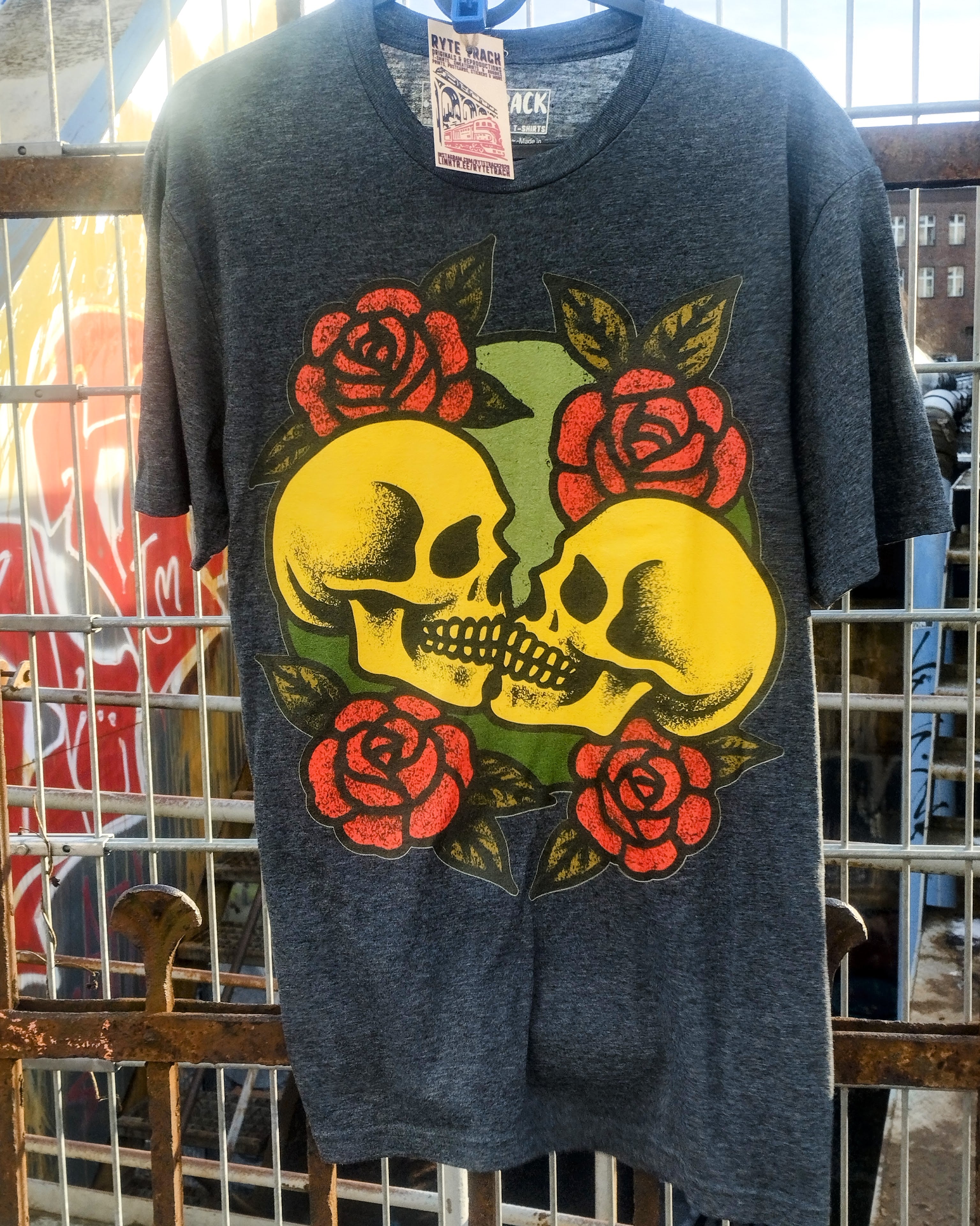 Gray t-shirt with a skull and roses design on a rack.