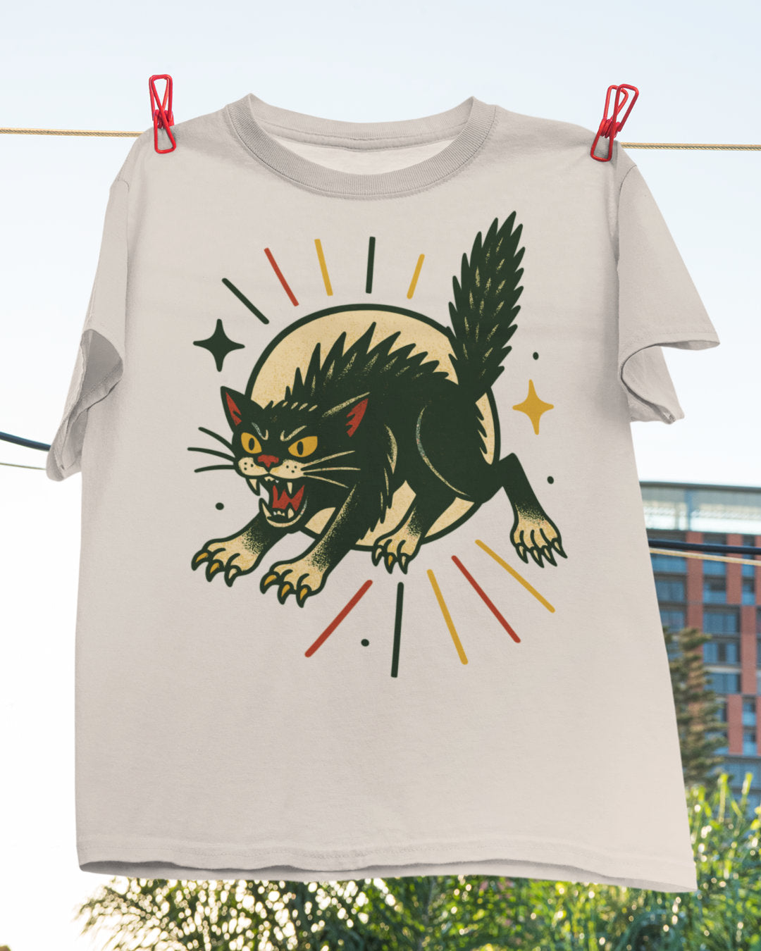 T-shirt with a black cat graphic on a clothesline with a cityscape background
