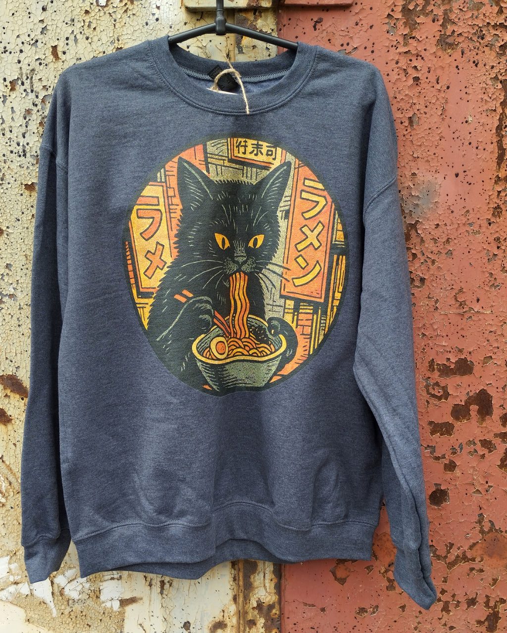 Black Cat Eating Ramen Sweatshirt hanging on a steel door