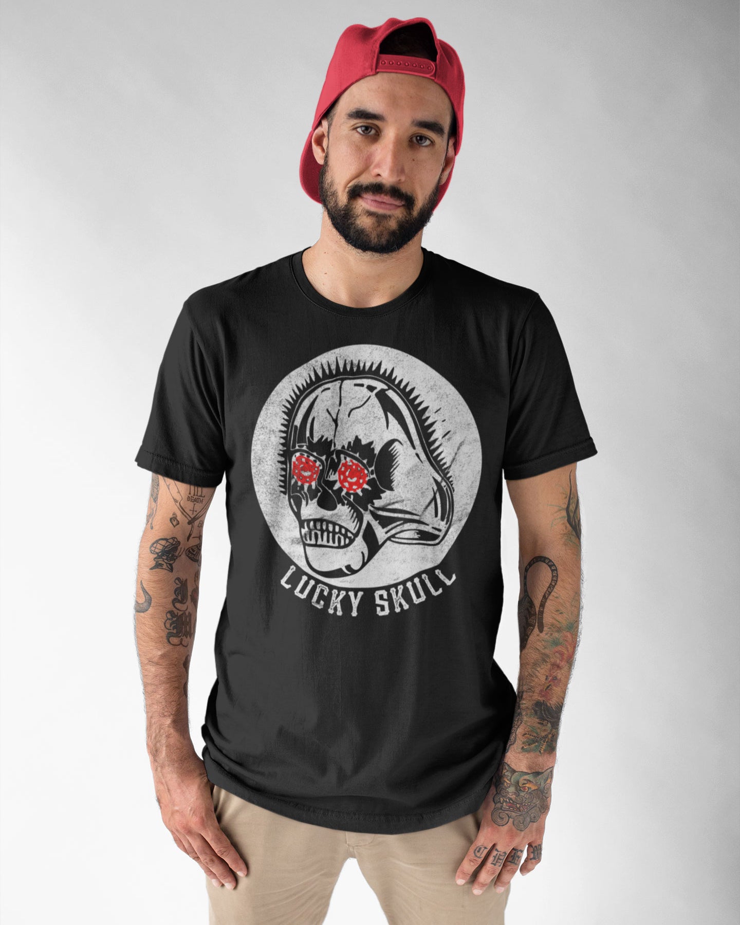 Man wearing a black t-shirt with 'Lucky Skull' design and a red cap on a gray background
