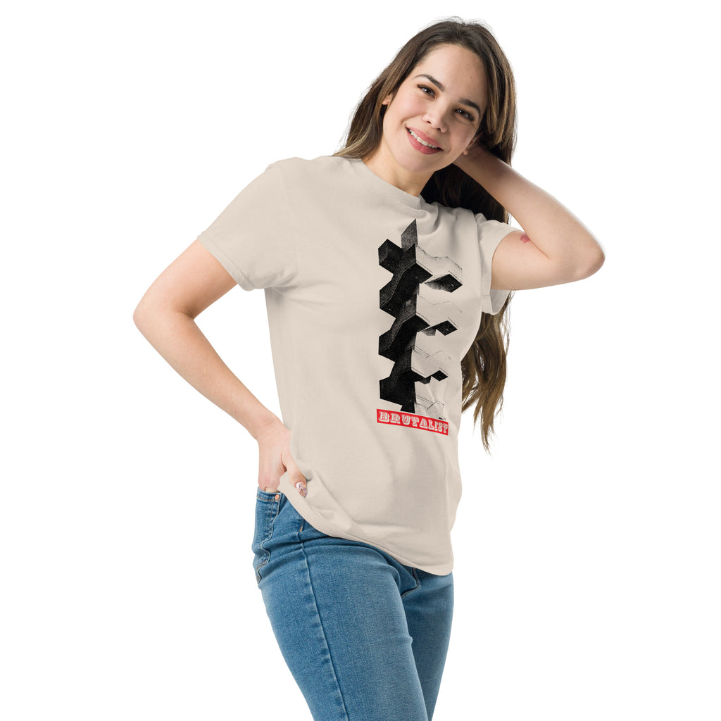 A woman modeling a light beige graphic t-shirt with a black geometric design and a red banner that reads 'Brutalist', paired with blue jeans against a plain white background.