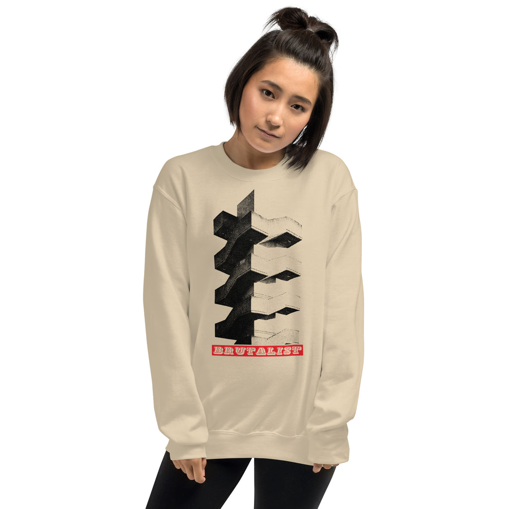 A woman modeling a beige crewneck sweatshirt with a black 3D geometric graphic and a red 'Brutalist' logo on the front, set against a plain white background.